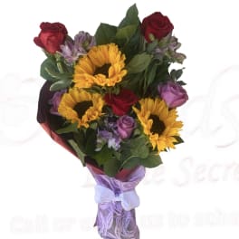 Bouquet of sunflowers, red roses, and purple flowers wrapped in lavender paper