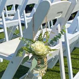 White rose in a small hanging glass vase on a chair