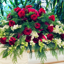 Large red rose casket spray with white flowers and greenery