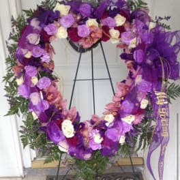 Purple floral wreath on a stand with roses and ribbon