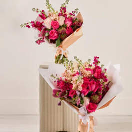 Two pink and peach flower bouquets wrapped in paper