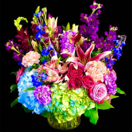 Colorful mixed bouquet in a glass vase with hydrangeas, roses, lilies, and stock