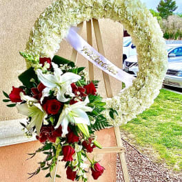Heart-shaped floral wreath with red roses and white lilies on an easel