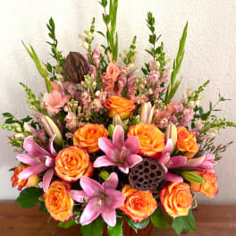 Orange roses and pink lilies in a wooden vase arrangement