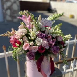 Pink and white mixed flower bouquet in a round box with a ribbon
