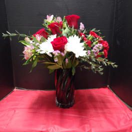 Red roses and white daisies arranged in a tall black vase