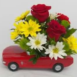 Red roses and yellow-white daisies arranged in a red toy car