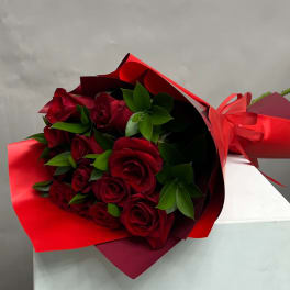 Bouquet of red roses wrapped in red paper with a ribbon