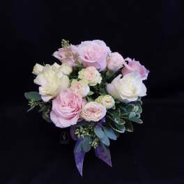 Bouquet of pale pink and white roses with a purple ribbon