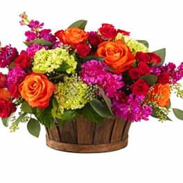 Mixed bouquet of roses and bright filler flowers in a wooden basket