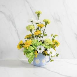 Yellow and white daisy bouquet in a blue mug with a green polka-dot bow