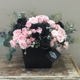 Pink and black rose arrangement in a black box