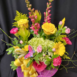 Bright mixed bouquet with yellow roses, pink blooms, and a purple ribbon wrap