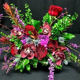 Red roses and purple orchids in a low floral arrangement