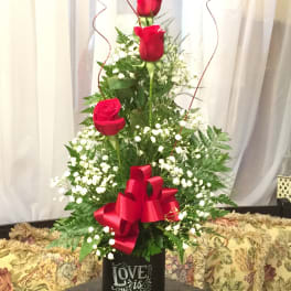 Tall arrangement of red roses with baby's breath in a black container