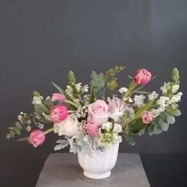 Pink and white flowers arranged in a white vase.