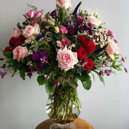 Large bouquet of pink, red, and purple flowers in a clear glass vase