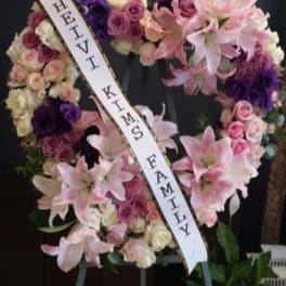 Heart-shaped floral wreath with pink lilies and roses on an easel