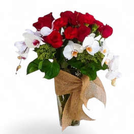 Red roses and white orchids in a glass vase with a burlap bow