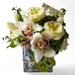 White orchids and pale roses arranged in a clear square vase