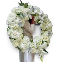 Large white floral wreath with lilies and roses around a person
