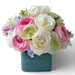 Pink and white roses with pale orchids in a teal square vase