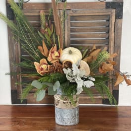 Autumn floral arrangement in a metal vase with a white pumpkin and dried accents