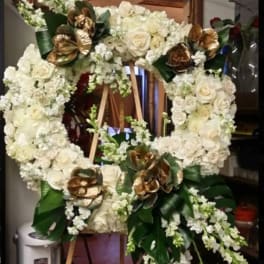Large white floral wreath on a wooden easel with gold accents