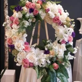 Large floral wreath on an easel with pink, white, and purple flowers