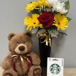 Bouquet of yellow and white flowers in a black vase beside a teddy bear