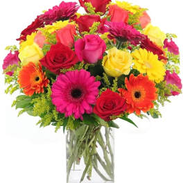 Mixed bouquet of roses, gerbera daisies, and mums in a clear glass vase