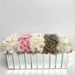 Pink roses and white flowers arranged in a long glass vase.