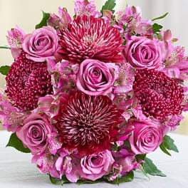 Pink roses and burgundy chrysanthemums arranged in a round bouquet.