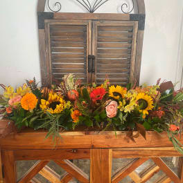Long autumn floral arrangement with sunflowers, roses, and marigolds in a wooden container