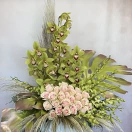 Tall floral arrangement with pale pink roses and green orchids in a vase