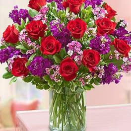 Bouquet of red roses and purple flowers in a glass vase