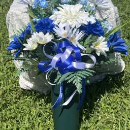 Blue and white floral arrangement in a green vase with ribbon
