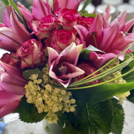 Pink roses and lilies arranged in a clear glass vase