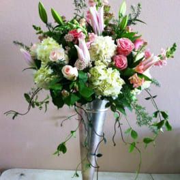 Tall floral arrangement in a silver pedestal vase with pink roses and lilies