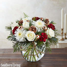 White and red floral arrangement in a clear glass vase with pinecones