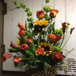 Mixed bouquet with orange roses, calla lilies, and sunflowers in a vase