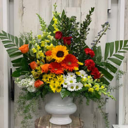 Large mixed flower arrangement in a white urn vase