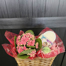 Pink flowering plant in a wicker basket with bath gift items