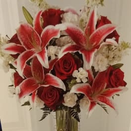 Red roses and white-red lilies in a clear glass vase