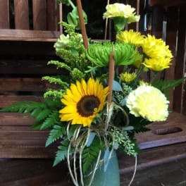 Sunflower and yellow carnation arrangement in a green vase