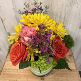 Mixed bouquet of roses, yellow daisies, and purple filler flowers in a vase
