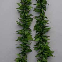 Two strands of green leaf garland laid on a plain gray background.