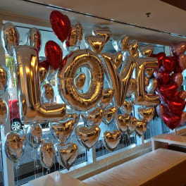 Gold and red heart-shaped balloons spelling LOVE