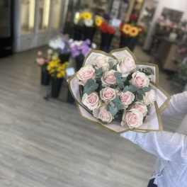 Handheld bouquet of pale pink roses wrapped in paper