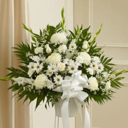 White floral standing arrangement with a ribbon on a pedestal